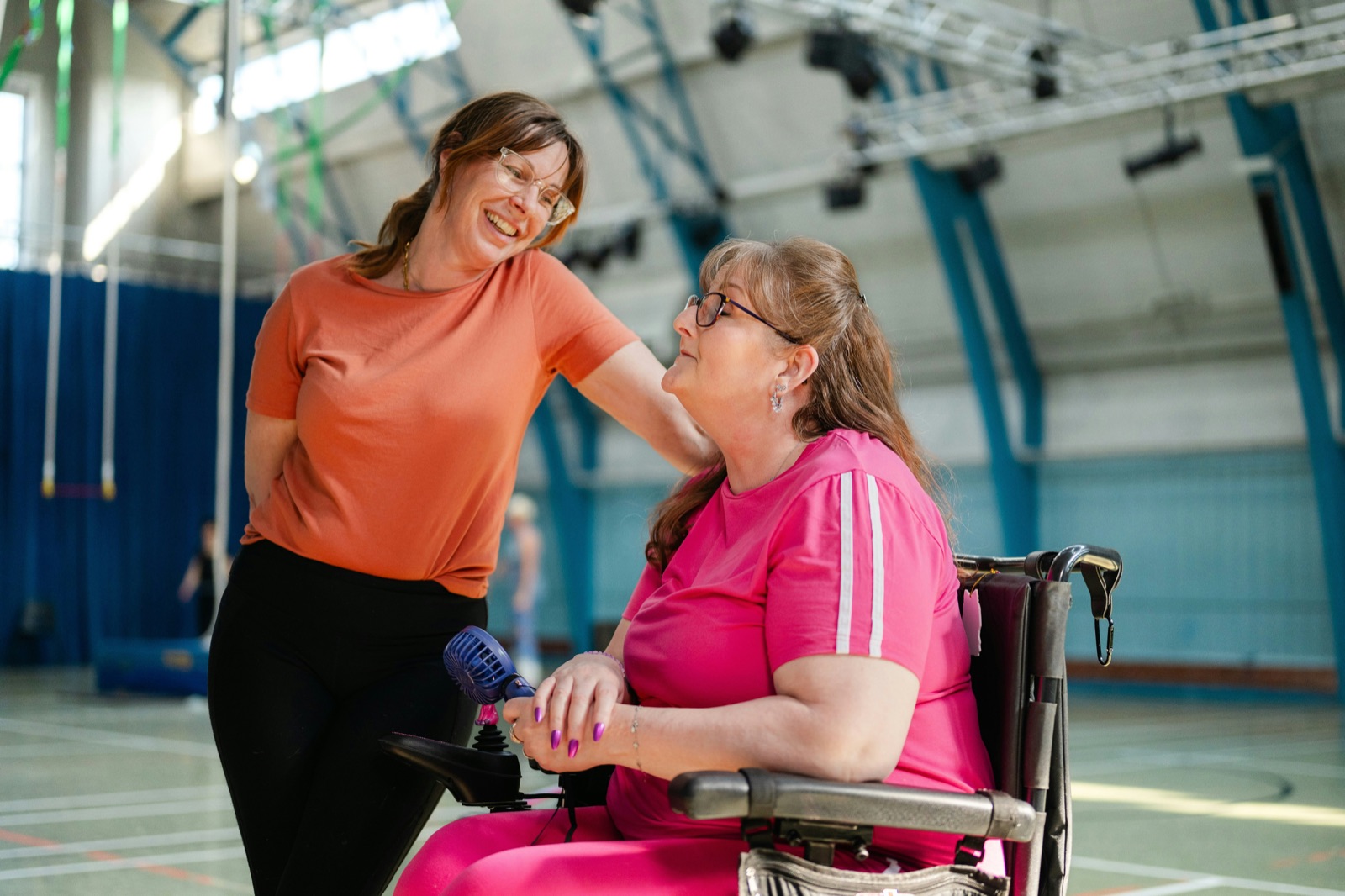 Two women sharing a moment of warm laughter together, one using a wheelchair